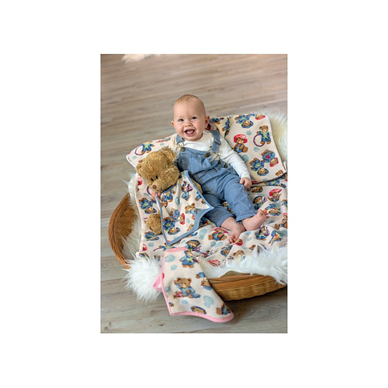 Малыш сидит в плетёной корзине на детском одеяле Feiler Mini LITTLE SKIPPERS с медвежатами-моряками; край одеяла с розовой каймой свешивается наружу