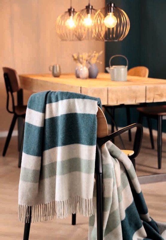 Плед Biederlack TEAL CHARMING перекинут через спинку стула у обеденного стола, бахрома свисает свободно