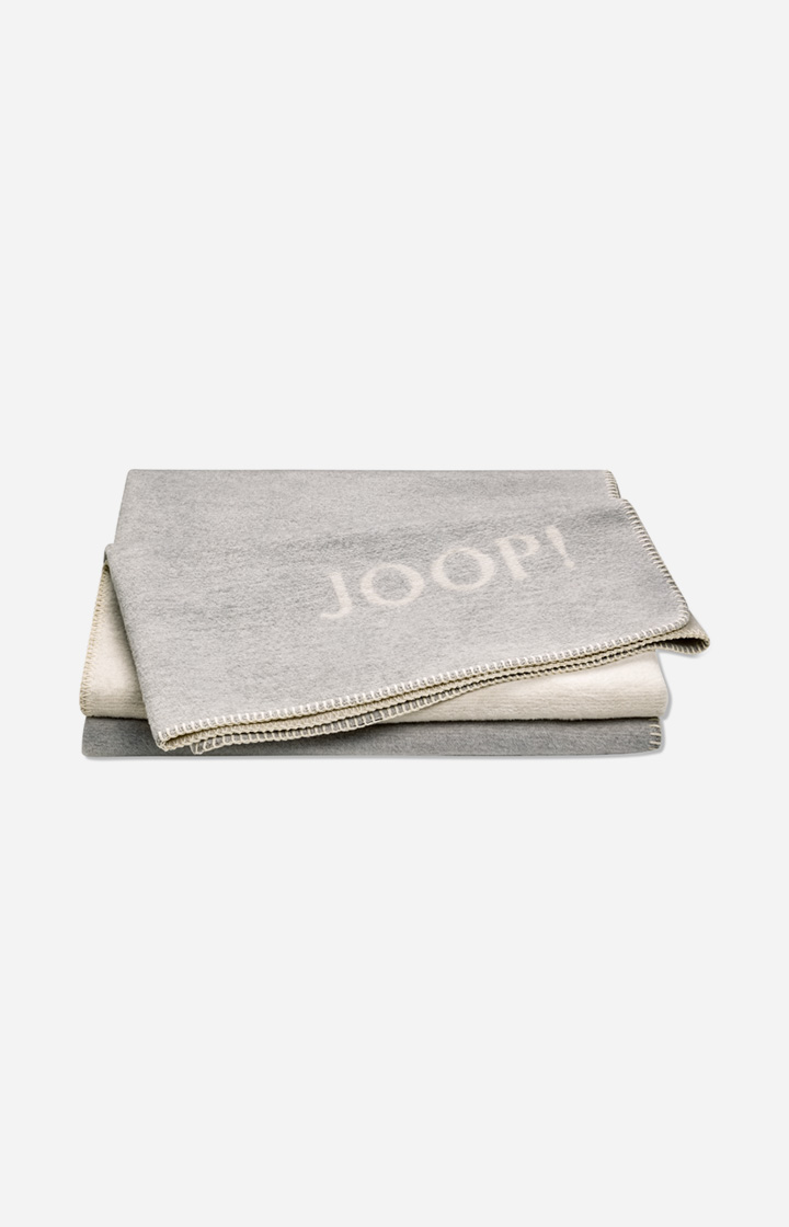 Плед JOOP! MELANGE-DOUBLEFACE в расцветке Stein-Silber, двусторонний, с бахромой и вытканным логотипом JOOP!, сложен веером
